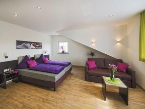 A modern bedroom with a large bed, a sofa, and a small table. - Gästehaus Stock (Friedrichshafen)