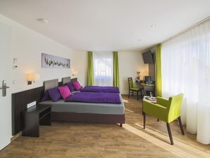 A modern hotel room with a large bed, a desk, a chair, and a TV. - Gästehaus Stock (Friedrichshafen)