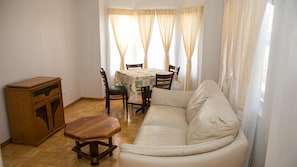 A living room with a sofa, wooden table, chairs, and a cabinet.