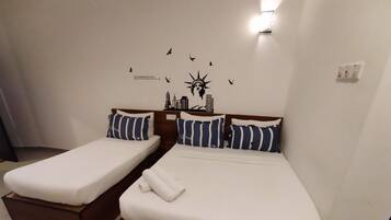 A hotel room with two single beds, each with a wooden headboard and striped pillows.
