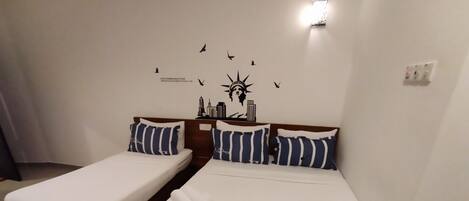 Habitación de hotel con dos camas individuales, cada una con cabecero de madera y almohadas a rayas.