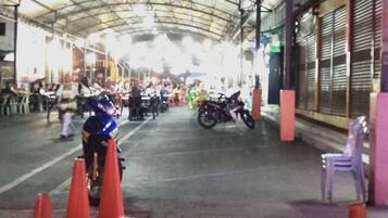 A covered outdoor area with tables and chairs, a motorcycle, and orange traffic cones.