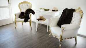 A room with two ornate white chairs with gold accents, a small white table, and a white desk with a vase of flowers. - Relais Inn Lucca (Lucca)