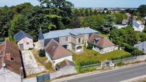 Una extensa propiedad con varias construcciones, incluyendo una casa principal con un jardín amplio y una edificación más pequeña con una torre.