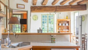 Una cocina con encimera de madera, un lavamanos, una ventana con vistas y un reloj en la pared.