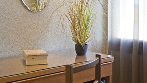 A wooden desk with a mirror, a potted plant, and a book. - Hostal Barris (Pals)