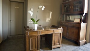 A wooden desk with a potted orchid, a private room door, and a wooden cabinet with glass doors. - Hostal Barris (Pals)