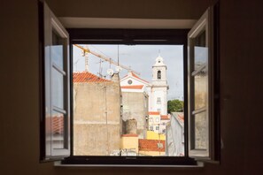 A view through an open window of a building with a bell tower, construction equipment, and a clear sky.