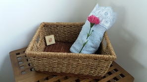A wicker basket with a blue towel and a pink flower.
