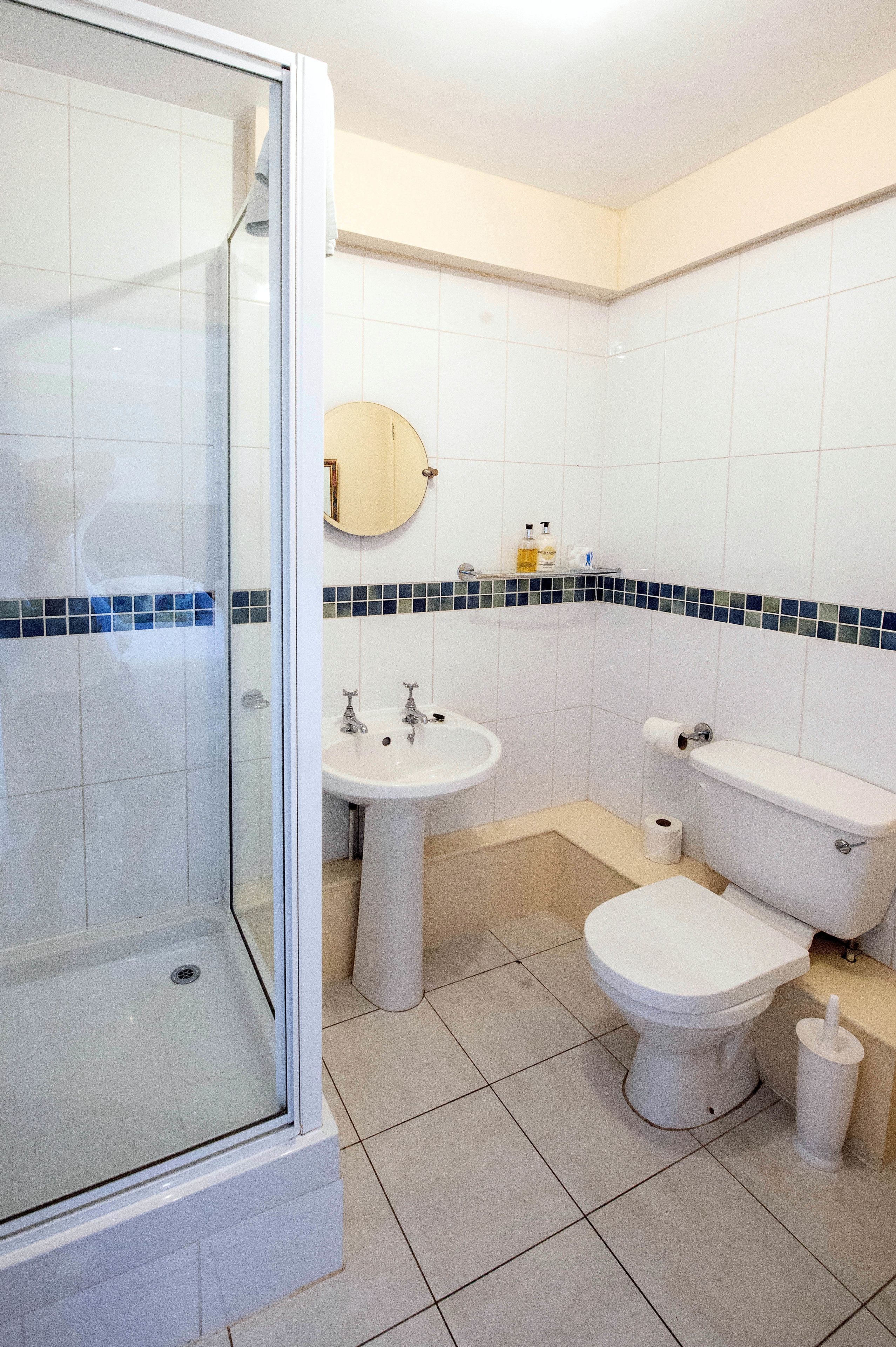 A bathroom with a glass-enclosed shower, a sink, and a toilet.