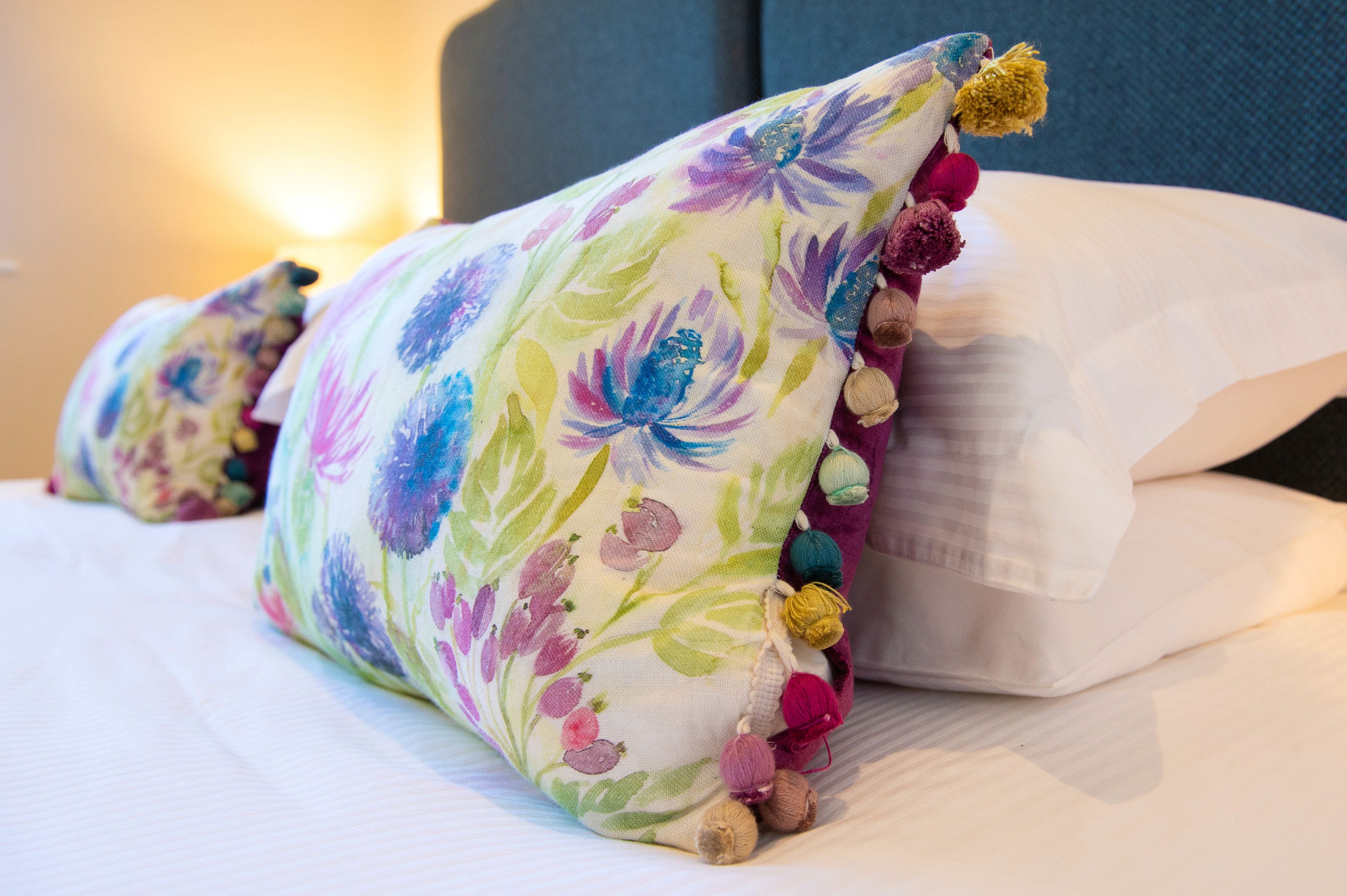 A bed with two decorative pillows featuring floral patterns and tassels.
