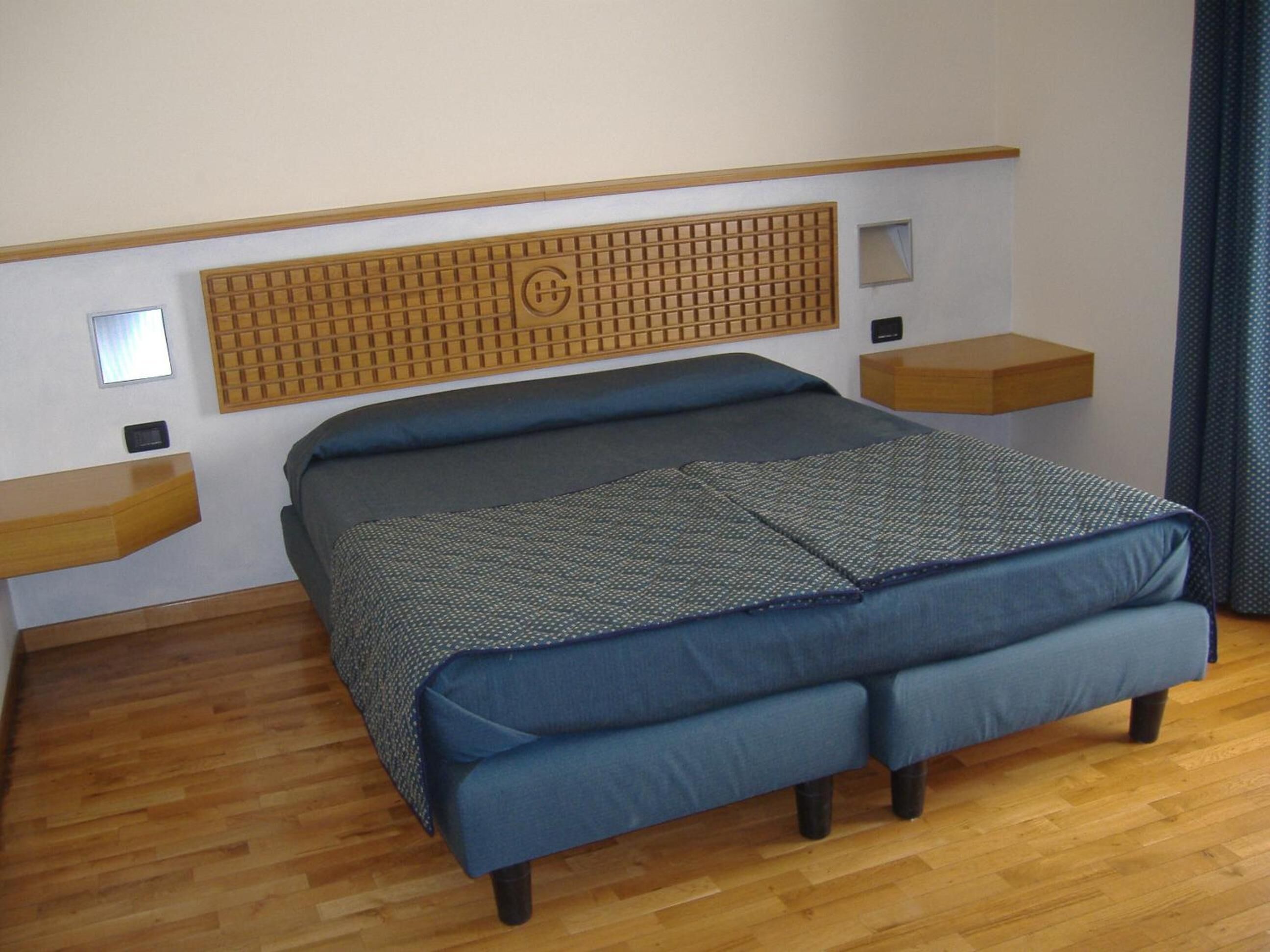 Een moderne slaapkamer met een groot bed, een houten hoofdbord, nachtkastjes en een houten vloer.