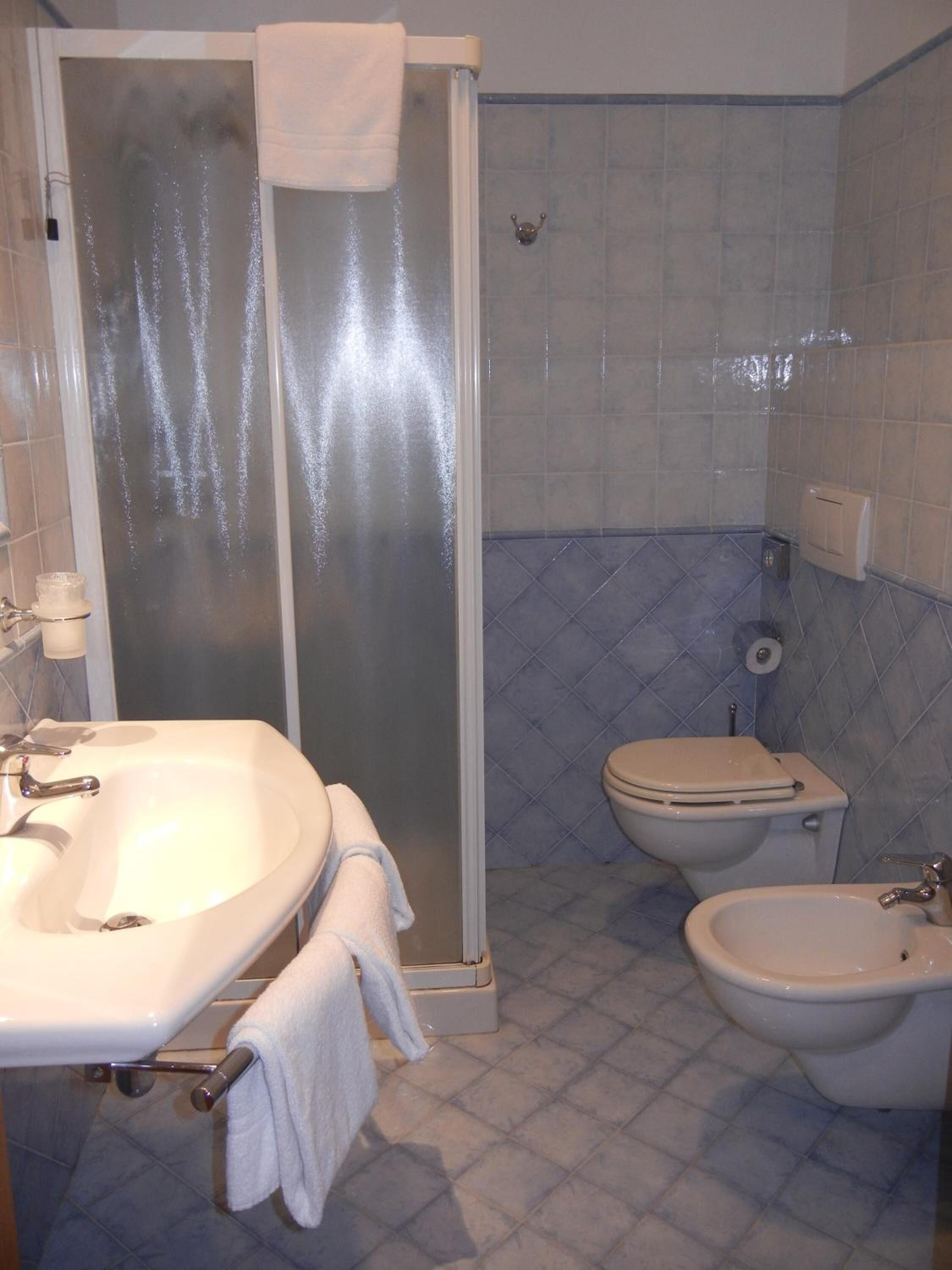 Un baño con cabina de ducha, lavabo, inodoro y bidé.