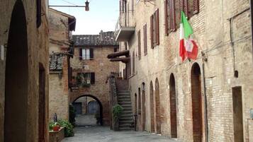 Un estrecho callejón con edificios de ladrillo, una escalera y una bandera.