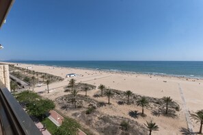 Ein Strand mit freiem Blick auf den Ozean, Palmen und einigen Strandsonnenschirmen.