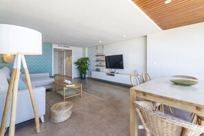 Ein modernes Wohnzimmer mit Sofa, Couchtisch, Fernseher und Essbereich.