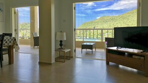 A spacious living area with a balcony offering a scenic view of a mountainous landscape.