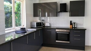 A modern kitchen with dark cabinetry, a built-in oven, and a microwave.