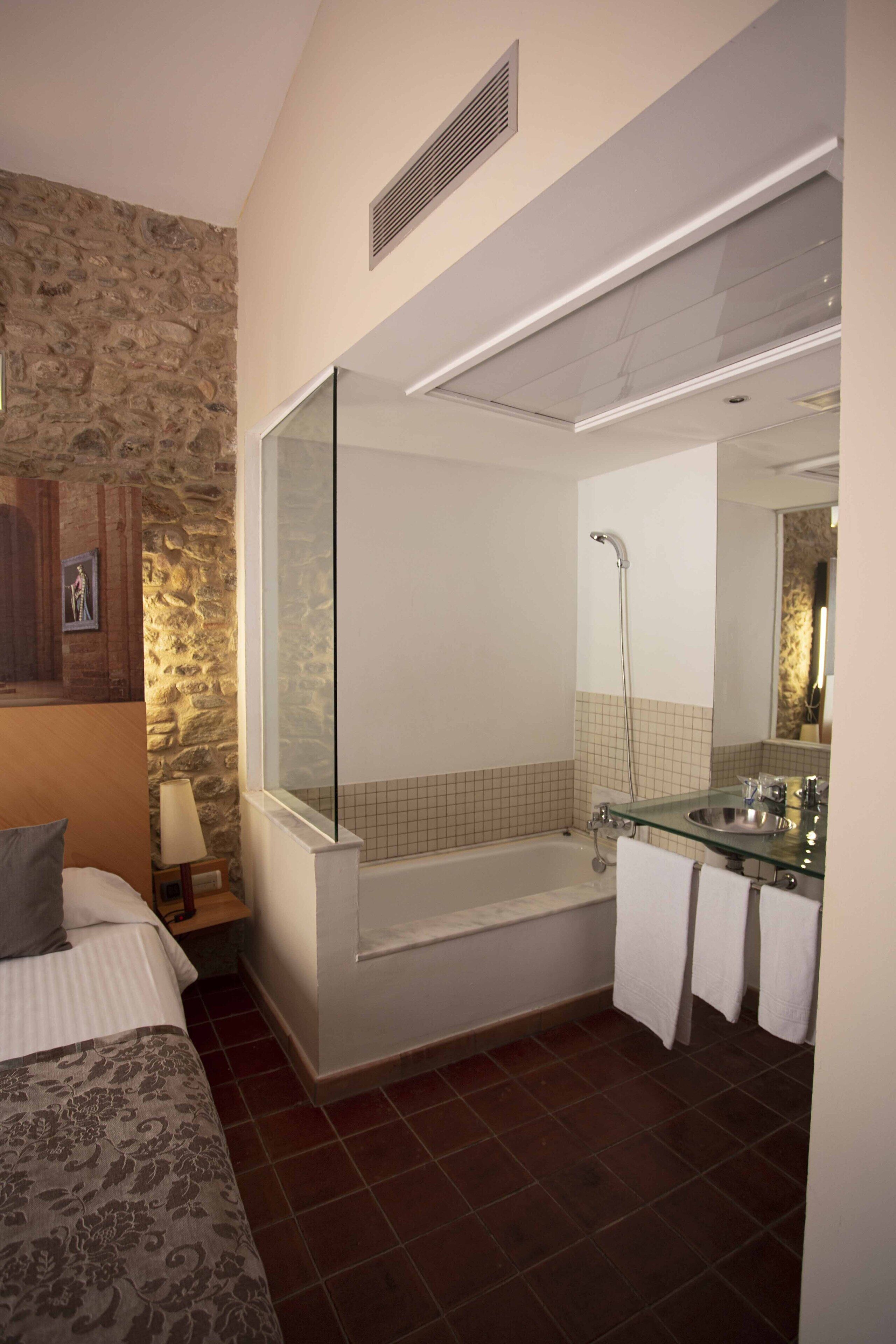 Une salle de bain moderne dotée d’une douche à parois de verre, d’une baignoire et d’un lavabo en verre.
