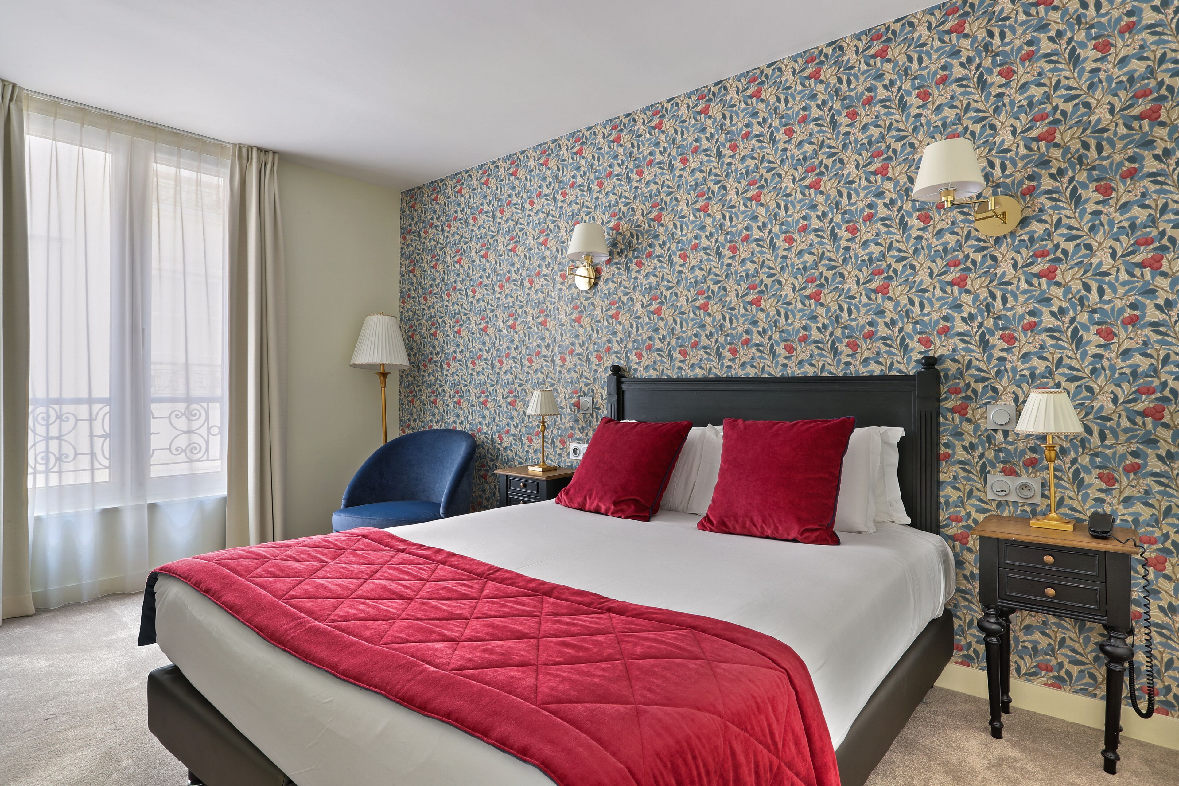 Une chambre d’hôtel avec un grand lit, une table de chevet, une chaise et une fenêtre avec des rideaux.