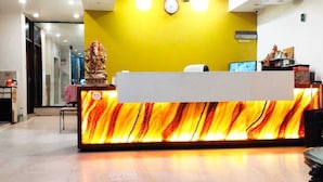 A reception desk with a marble-like design, a clock on the wall, and a statue in the background. - Hotel Indo continental (New Delhi)
