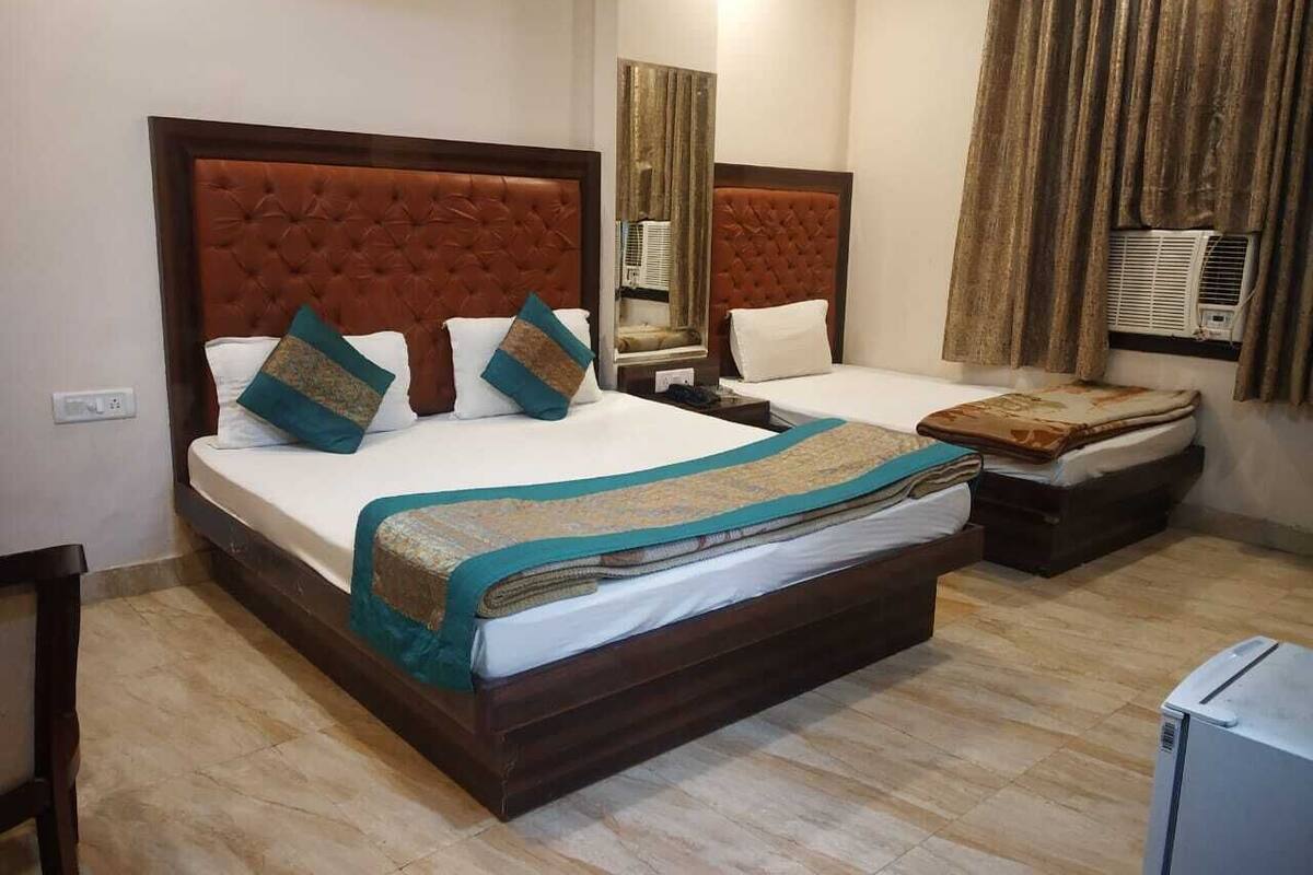 Ein Hotelzimmer mit zwei Betten, jeweils mit einer gebügelten Kopfstütze, einem großen Spiegel und einer Klimaanlage.
