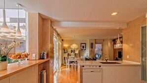 A modern kitchen with a central island, wooden cabinetry, and a view of the living area. - Spectacular duplex near Barcelona and beach (Tiana)