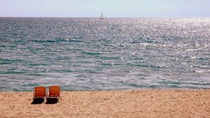 A beach with two sun loungers facing the ocean, a sailboat in the distance, and a clear sky. - Spectacular duplex near Barcelona and beach (Tiana)