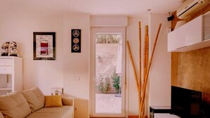 A modern living room with a sofa, a TV, and a door leading to a balcony. - Spectacular duplex near Barcelona and beach (Tiana)
