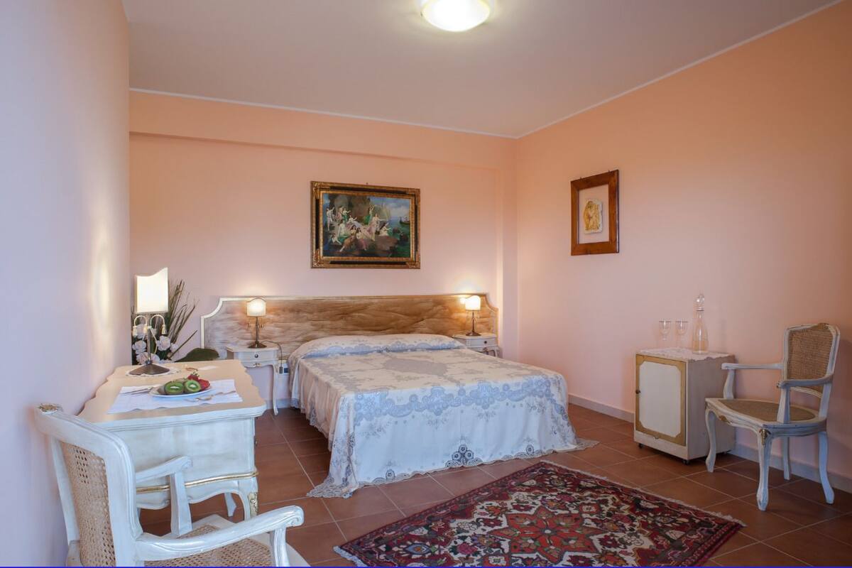 Une chambre à coucher avec un lit double, des tables de chevet, une chaise, une petite armoire et un tapis.