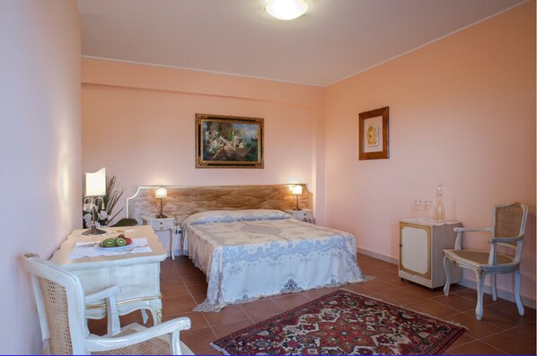 A bedroom with a double bed, bedside tables, a chair, a small cabinet, and a rug. - La Corte Di Opaka (Canosa di Puglia)