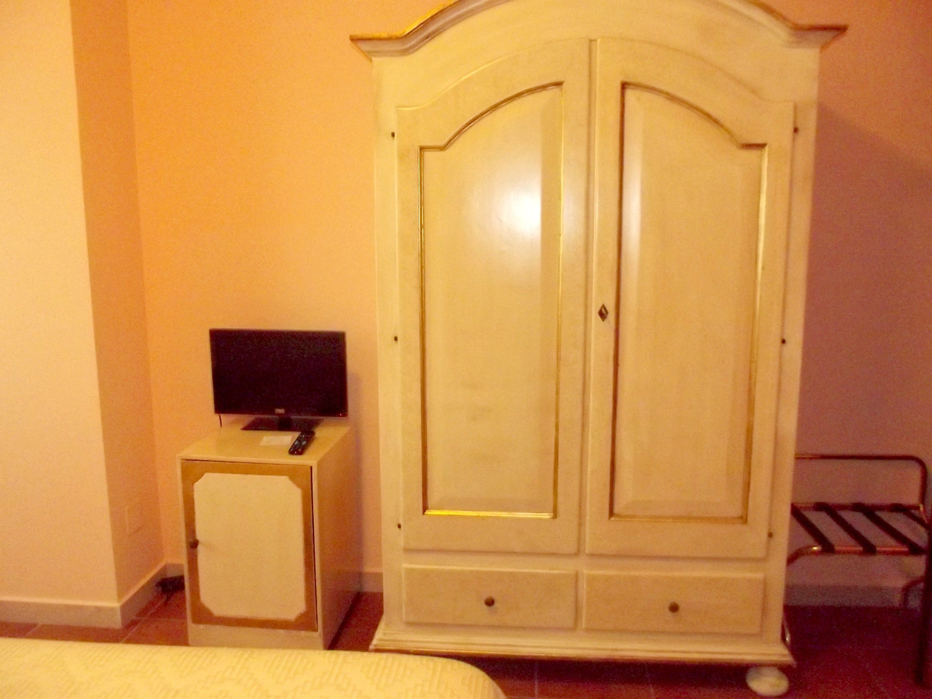 Une chambre avec un lit, un téléviseur posé sur une petite table et une grande armoire.