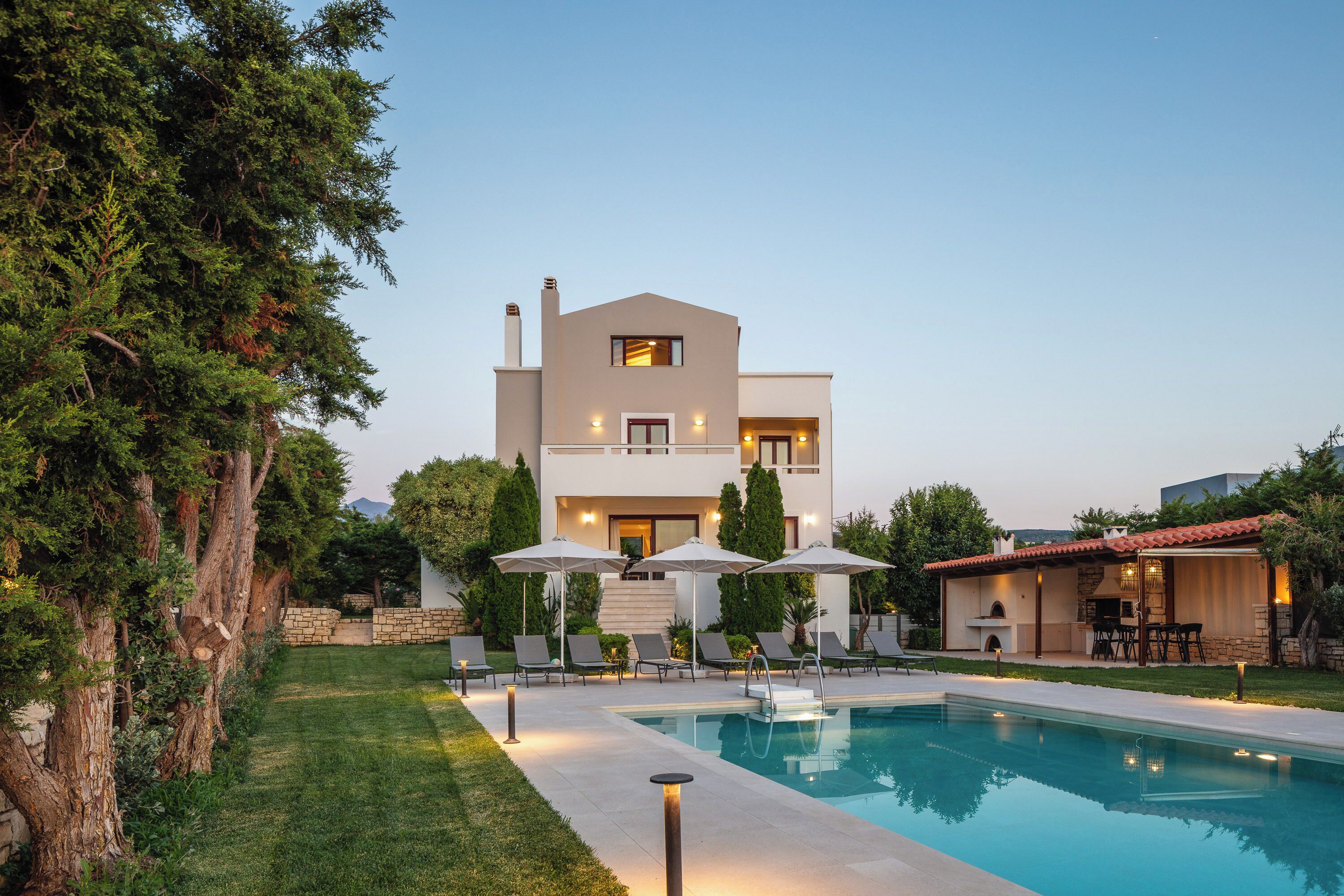 A modern two-story house with a swimming pool, outdoor seating, and a barbecue area.
