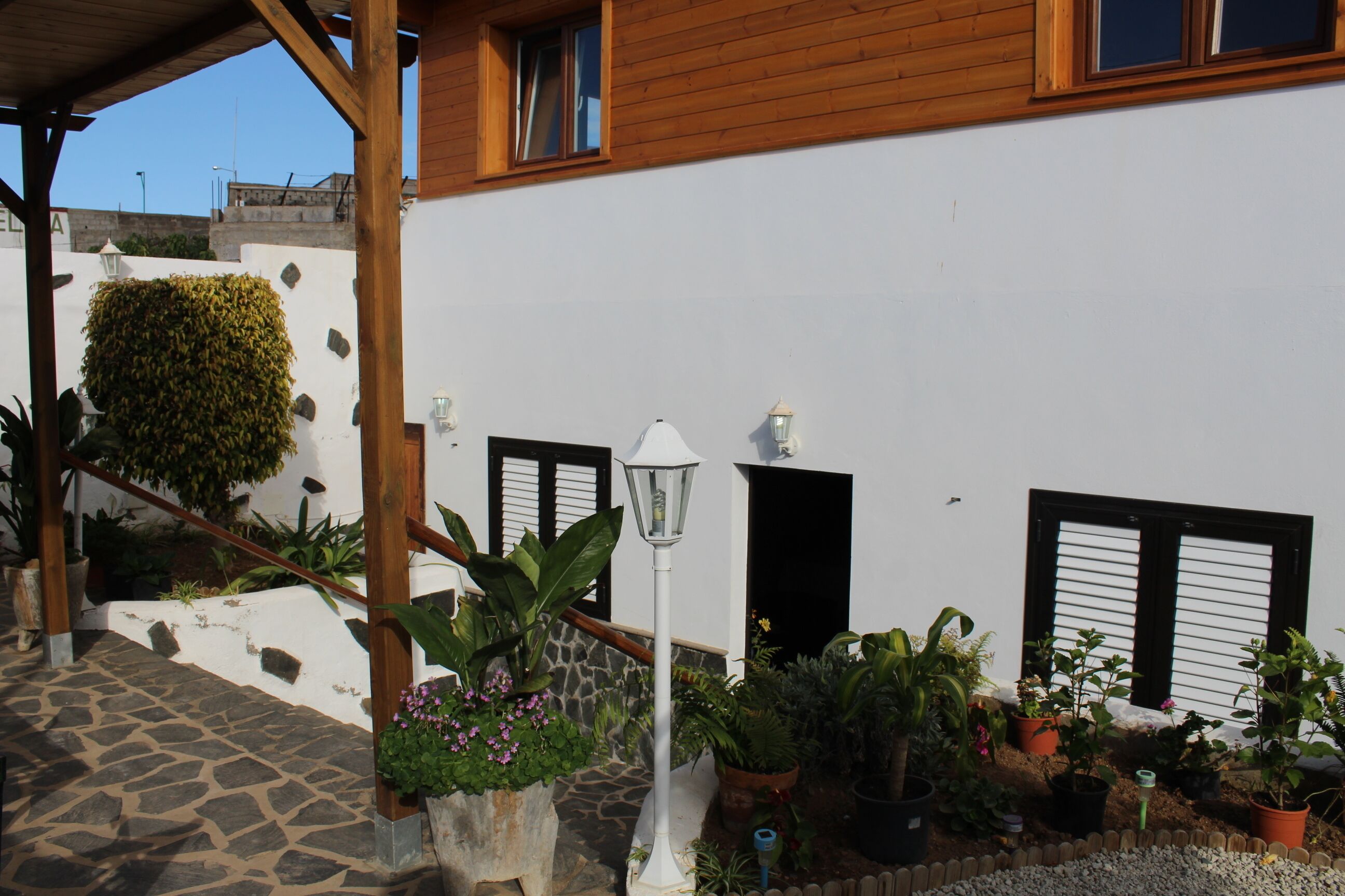Un edificio blanco con vigas de madera, una escalera de piedra y macetas con plantas.