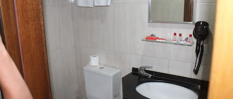 Casa de banho com sanita, lavatório e espelho.