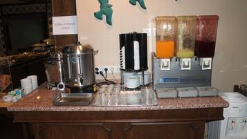 A buffet setup with a coffee maker, juice dispensers, and a sign indicating 'CORBA SERVISIMIZ VARDIR'.