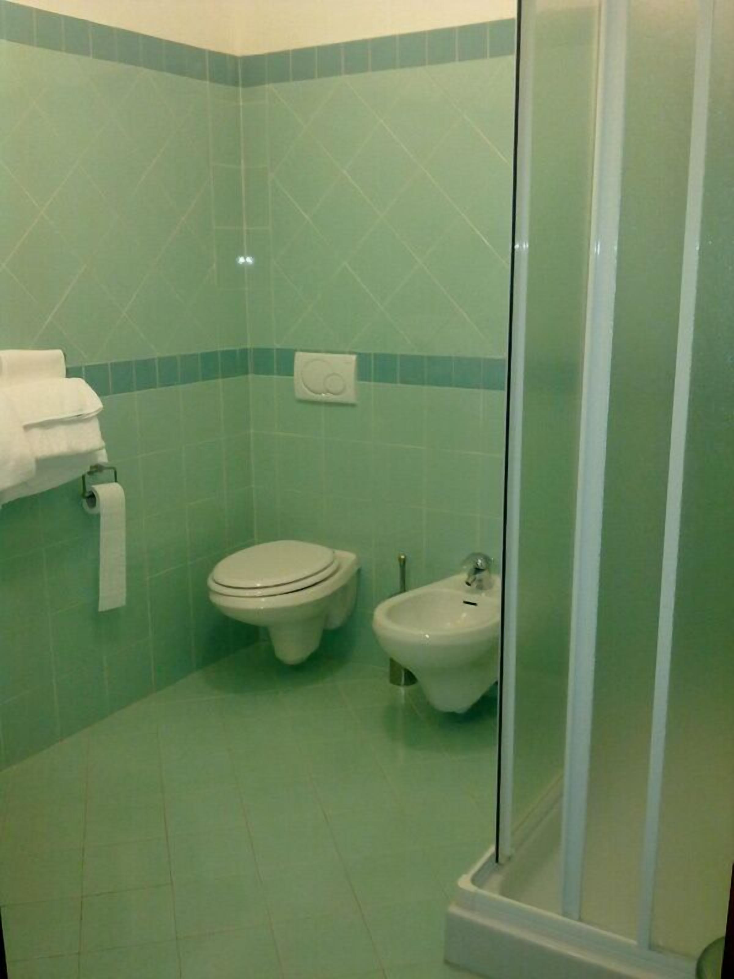Un baño con inodoro, bidé y cabina de ducha de cristal.