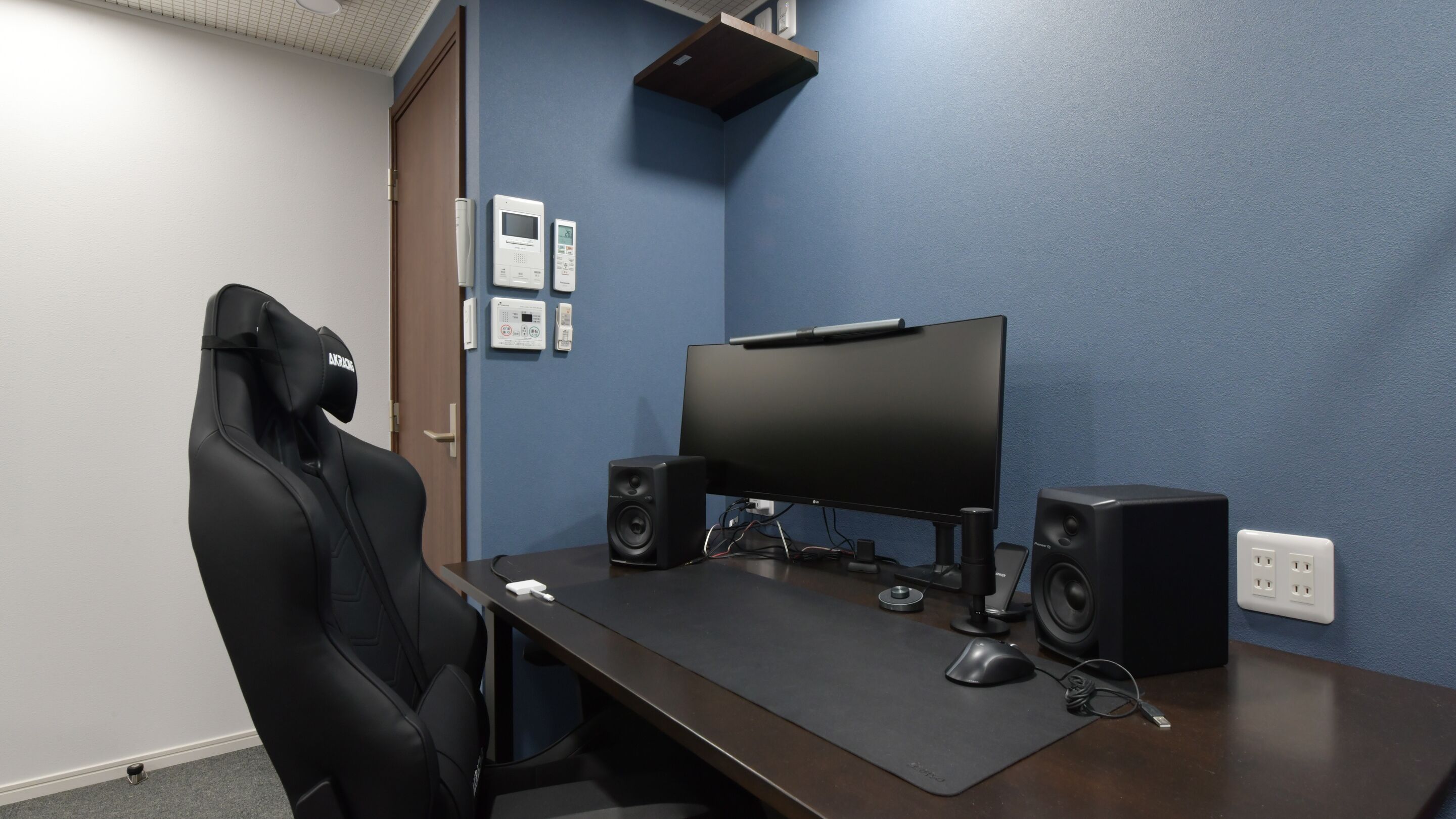 Una silla gamer, un escritorio con monitor de computadora, dos altavoces y un ratón.