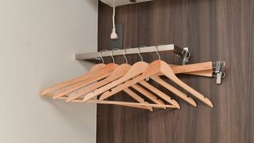 A wooden clothes rack with multiple hangers against a dark wooden wall.