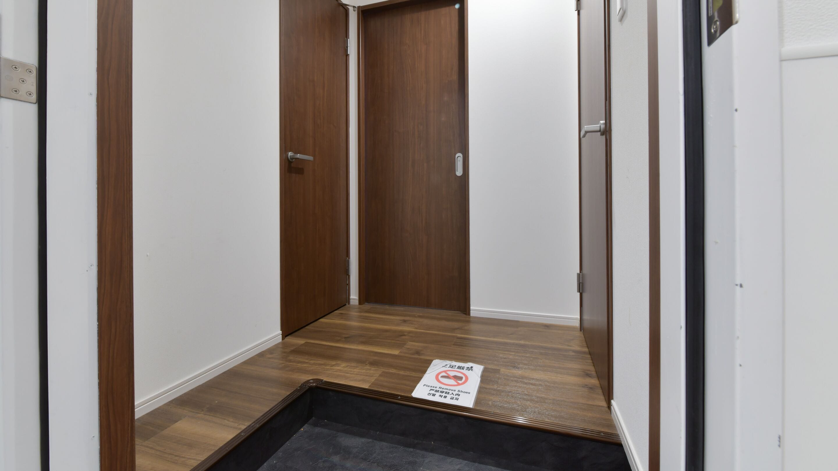 A narrow hallway with wooden doors and a sign on the floor.
