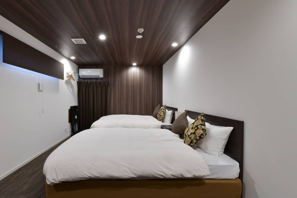 A modern hotel room with a large bed, a desk, and a built-in air conditioning unit.