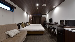 A modern hotel room with a large bed, a sofa, a desk with a computer and a TV, and a kitchenette. - Villa Front Kyoto Seimei (Kyoto)