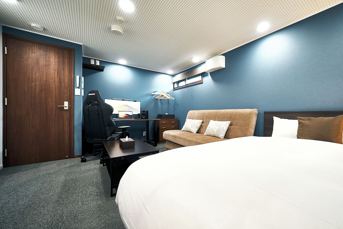 Habitación de hotel con una cama grande, un escritorio con ordenador, una silla y un armario.