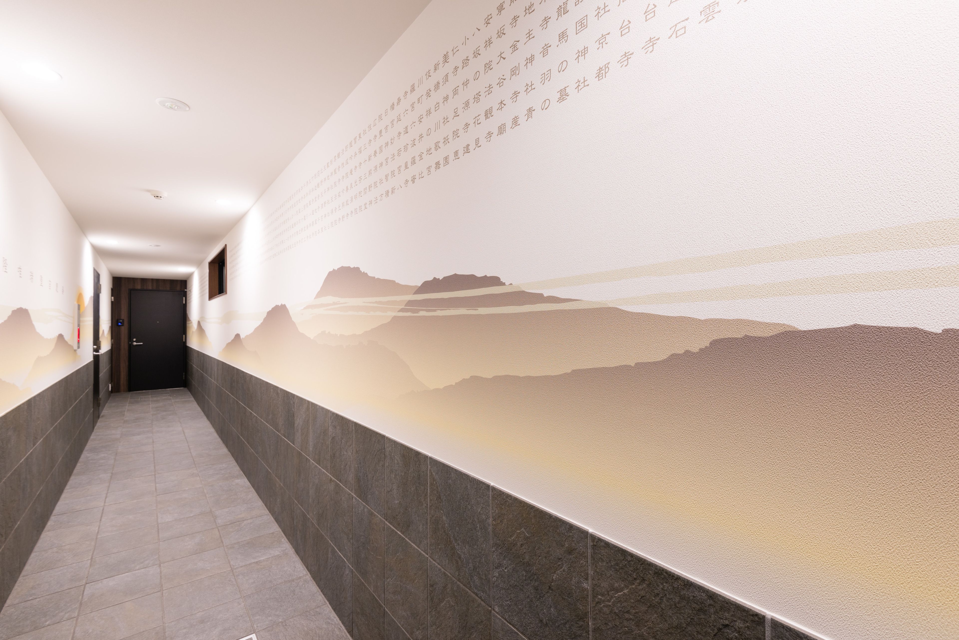 A hallway with a textured wall and a door at the end.