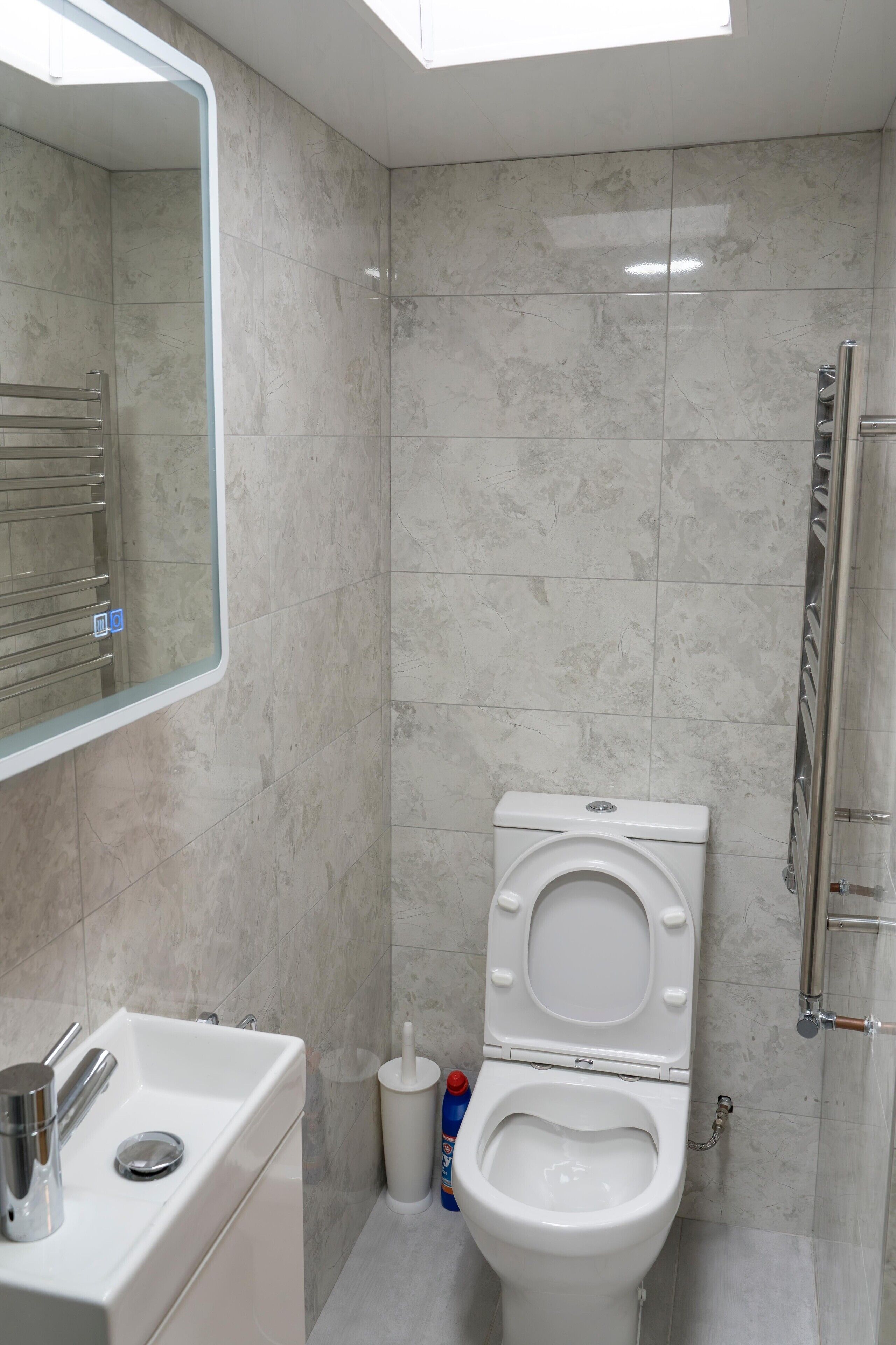 Een moderne badkamer met toilet, wastafel en spiegel.