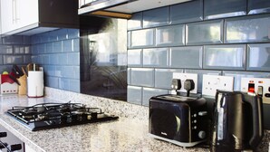 A kitchen with a gas stove, a toaster, and a coffee maker on a granite countertop.
