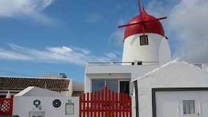 Un bâtiment blanc avec un moulin à vent rouge, une porte rouge et une petite fenêtre.
