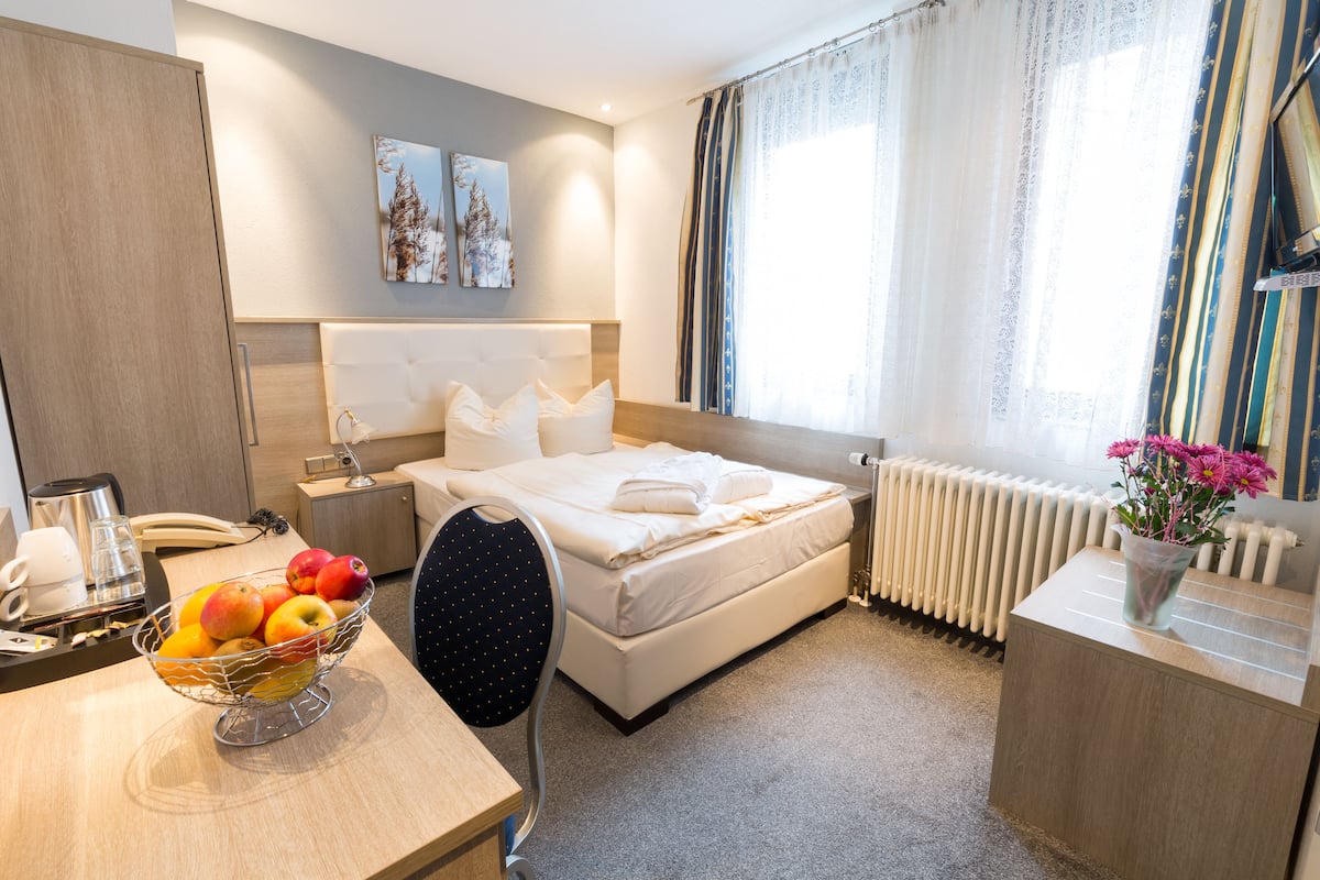 A hotel room with a bed, bedside table, and a fruit bowl.