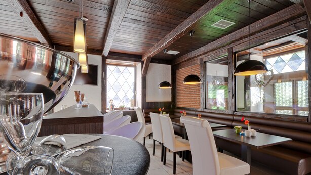 A restaurant with a rustic interior, featuring exposed wooden beams, a brick wall, and a mix of modern and traditional furnishings. - Bavaria Hotel Superior (Stuttgart)