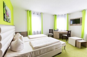 A hotel room with two beds, a desk, a chair, and a TV.